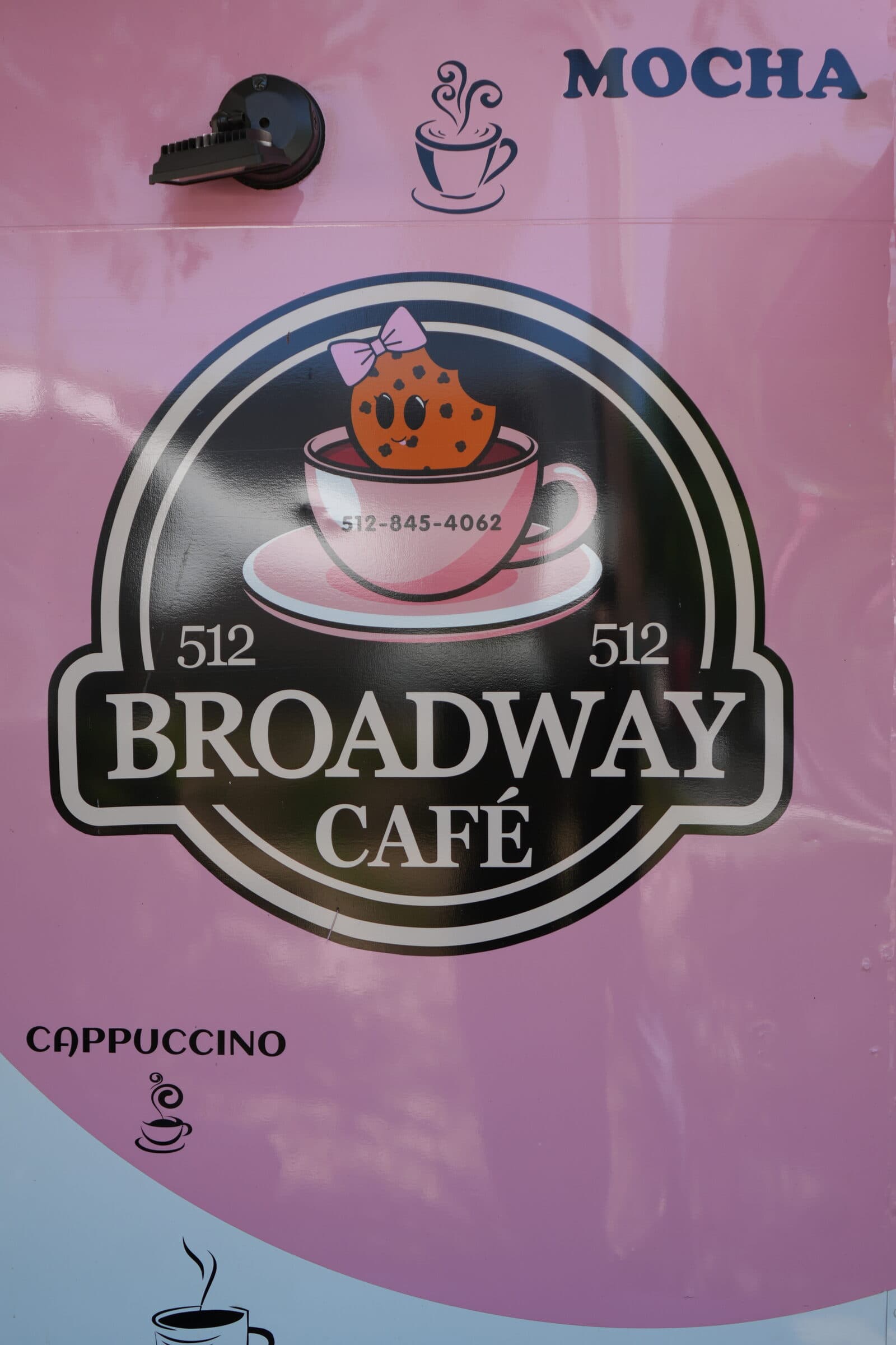Close-up of the Broadway Café truck logo, a pink coffee cup with a coffee bean character