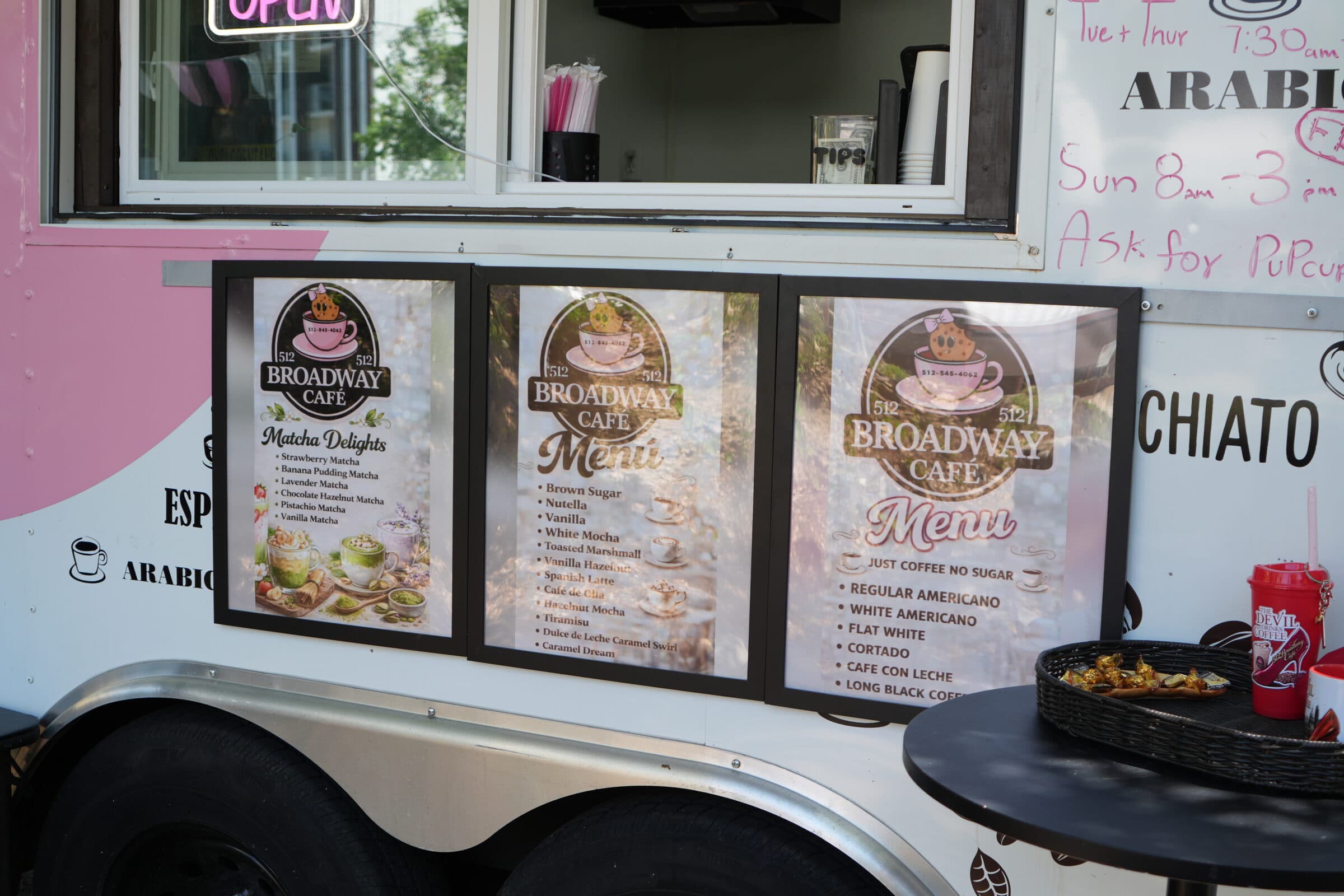 Three printed Broadway Café menu boards mounted on the side of the coffee truck