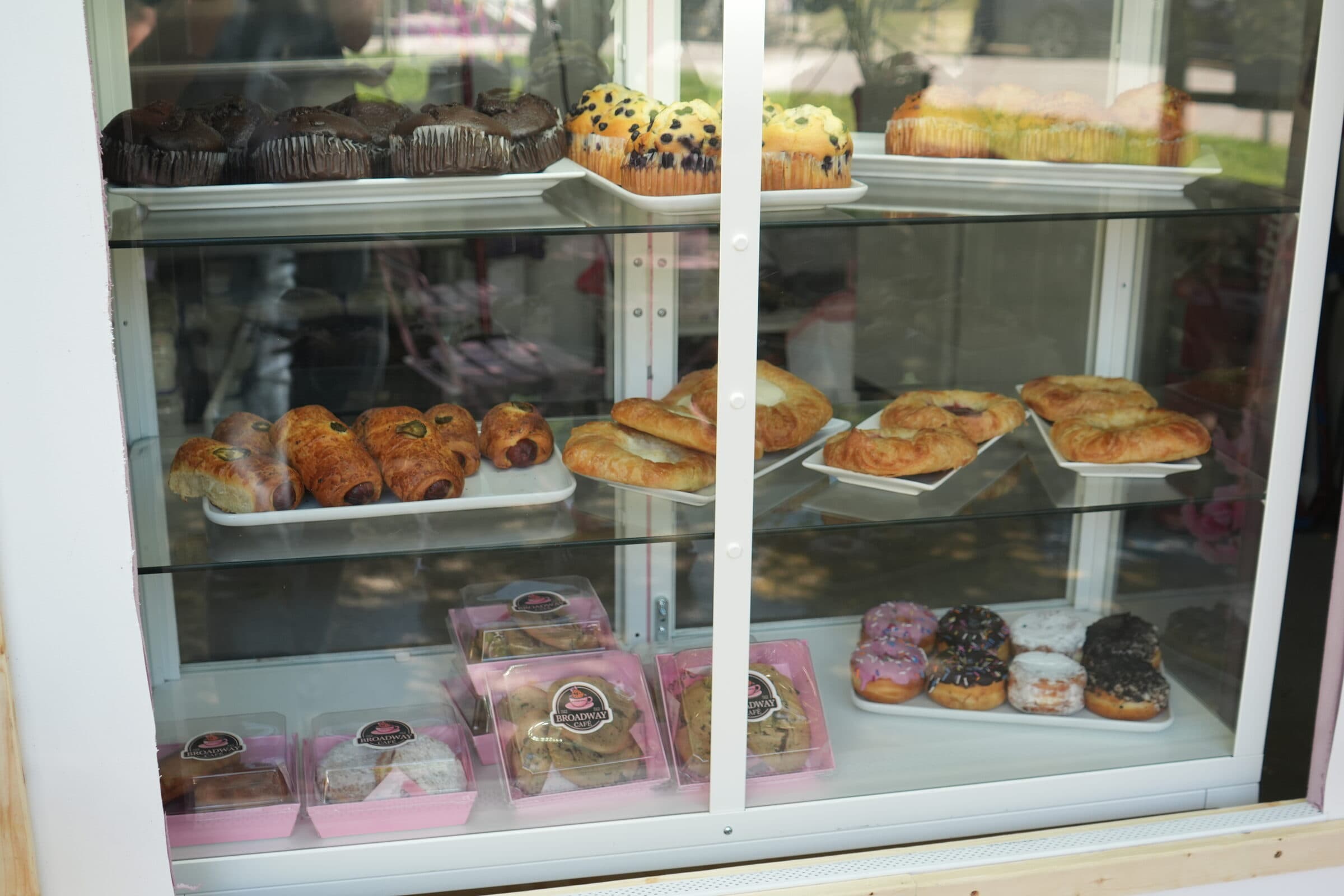 Counter case stocked with croissants, kolaches, muffins, and decorated cookies