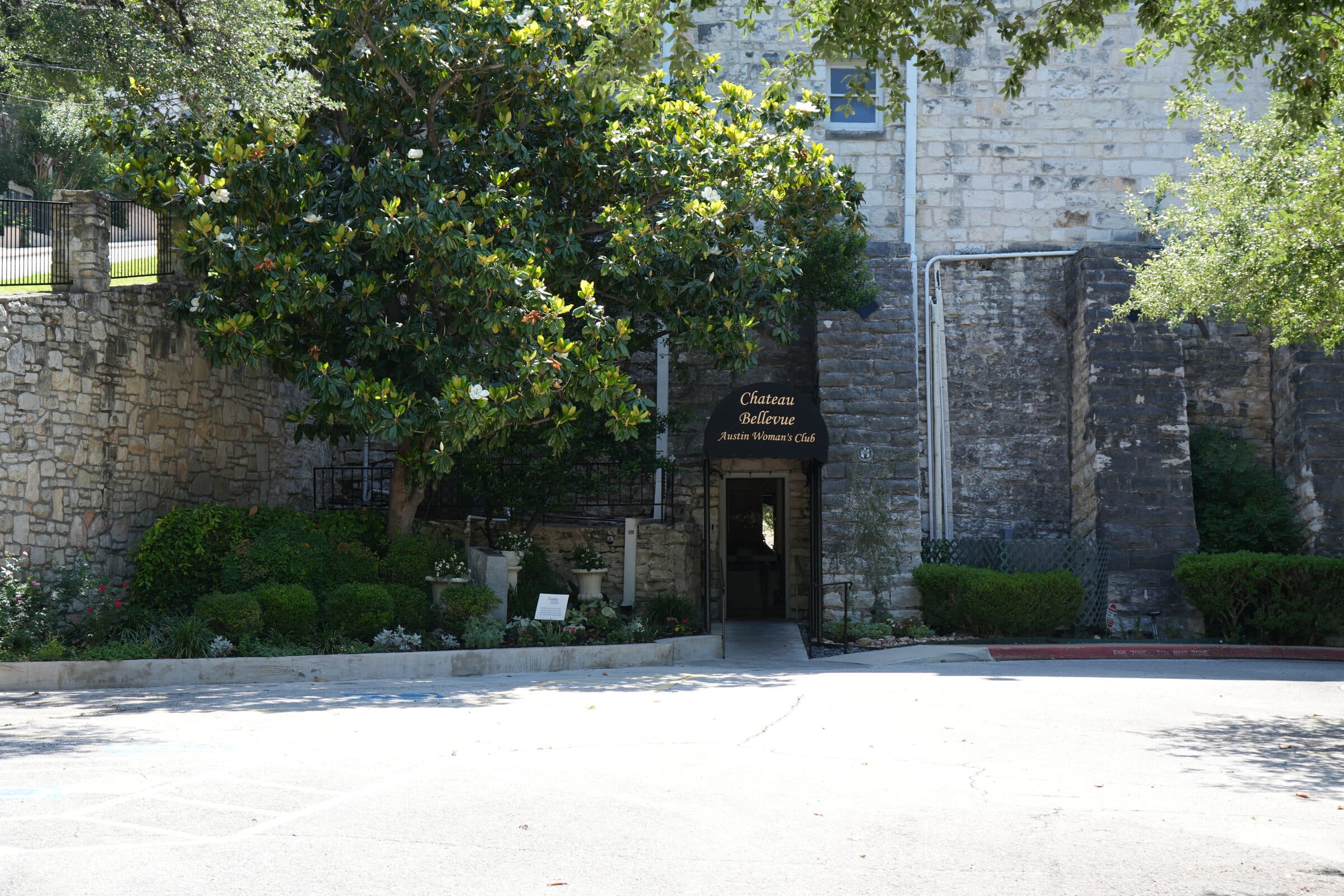 Stone entrance of Chateau Bellevue, the historic venue adjacent to the ANW lot, framed by magnolia foliage
