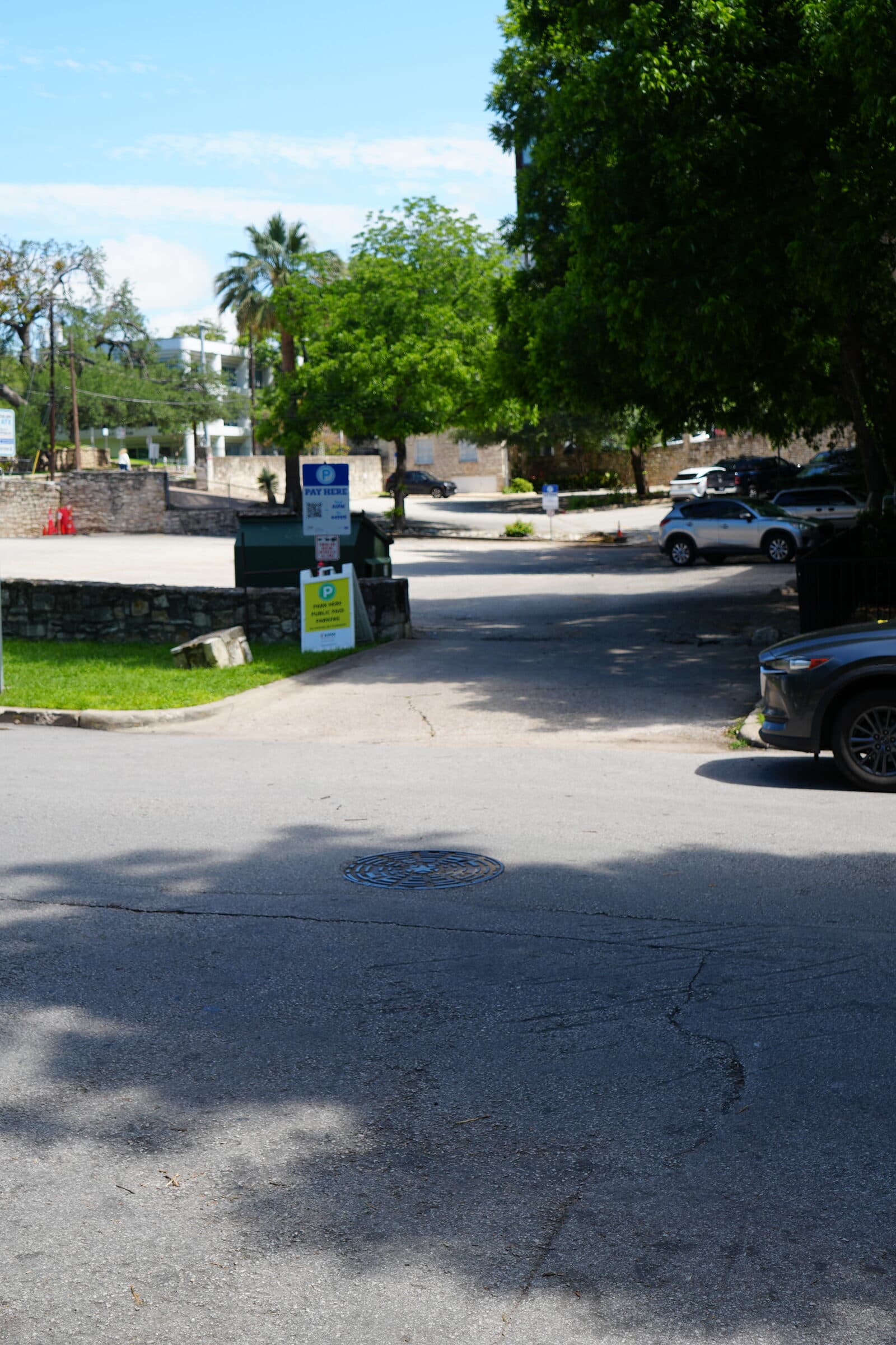 The ANW lot at quiet midday, palm trees and stone walls framing the surface spots
