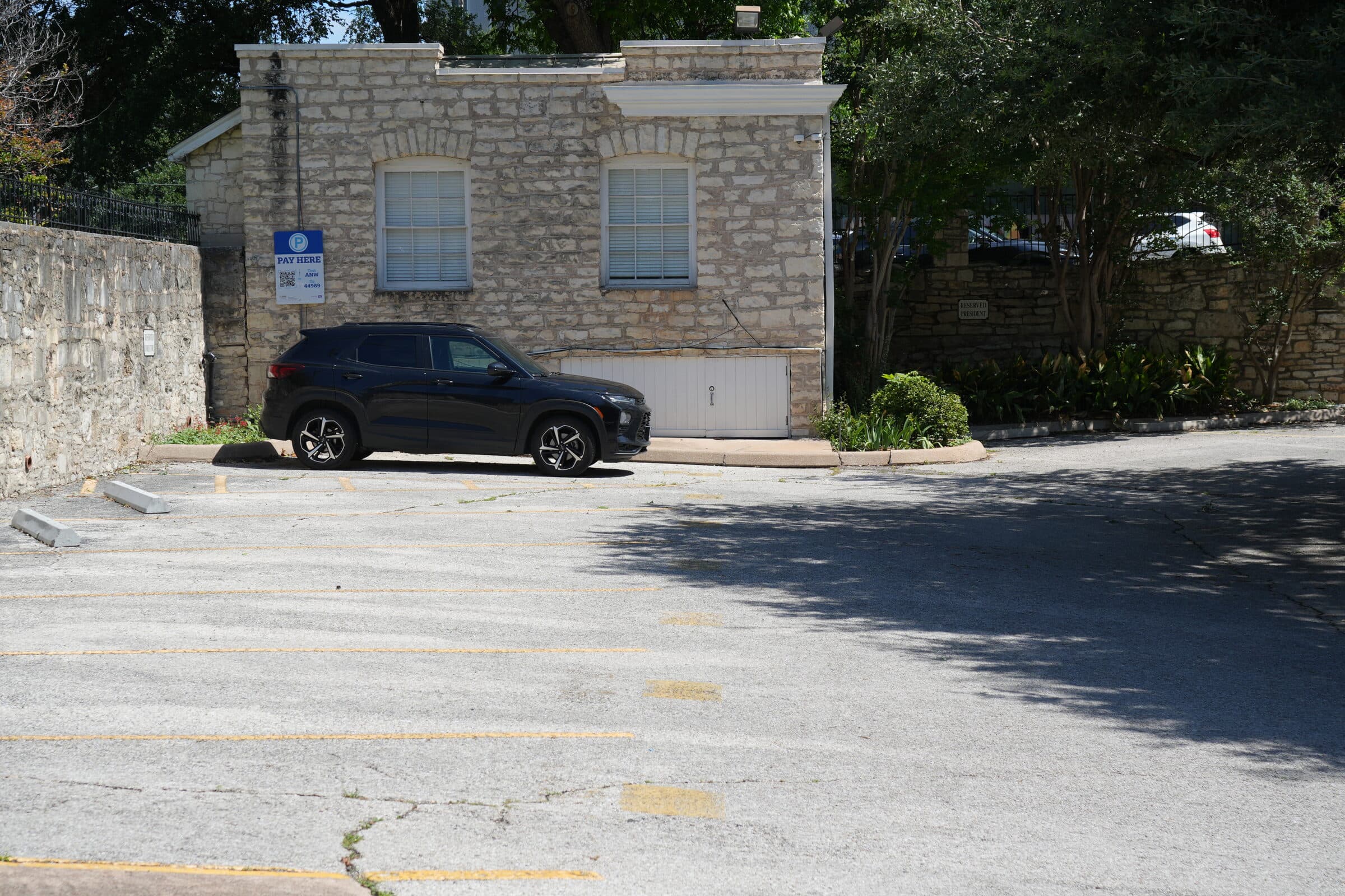 A single car parked beside the limestone kiosk on the ANW lot, mid-morning